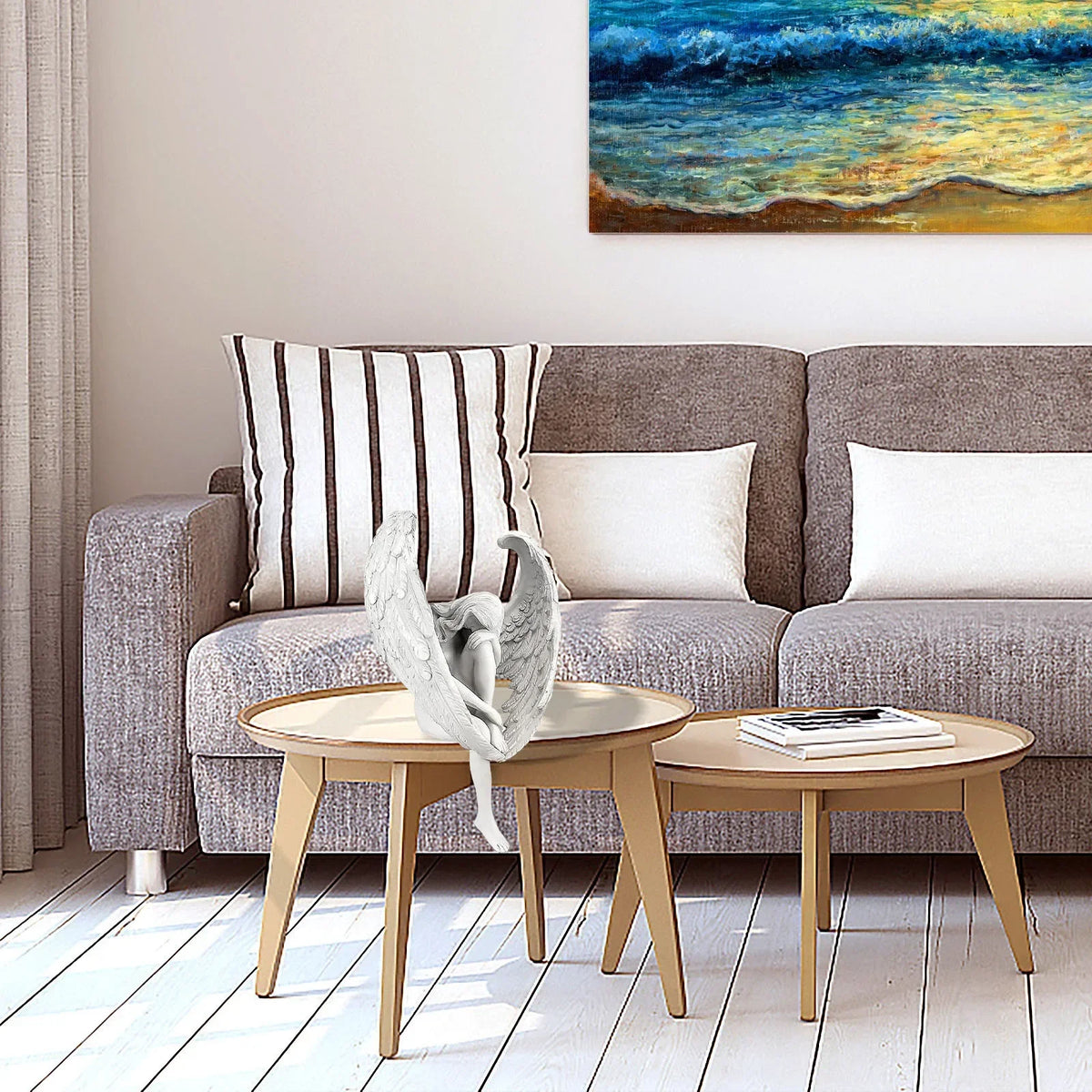 Gray sofa with striped pillow and white cushions, wooden coffee table, and painting of a beach scene.