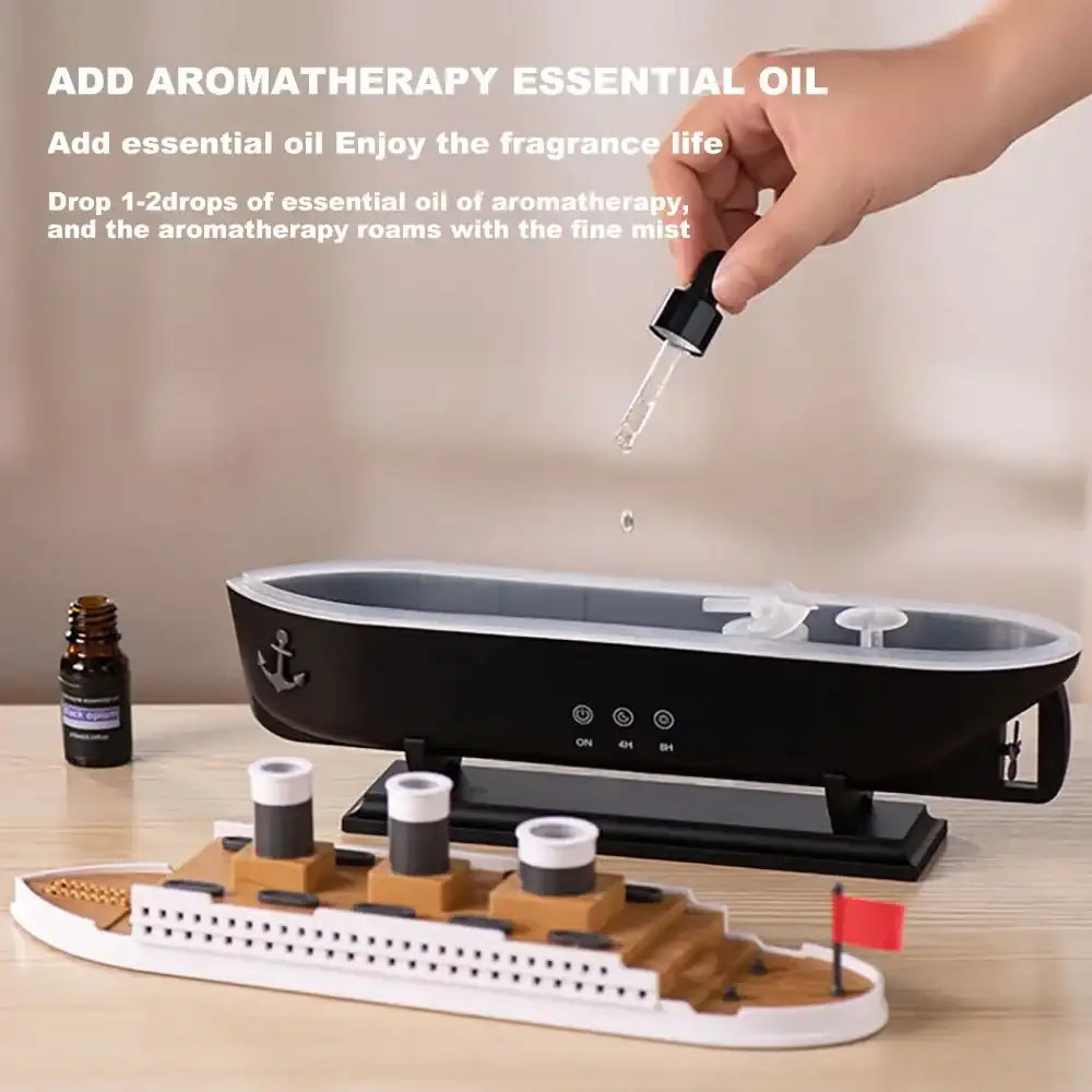 Aromatherapy diffuser with a hand adding essential oil and a bottle of essential oil on a wooden surface.