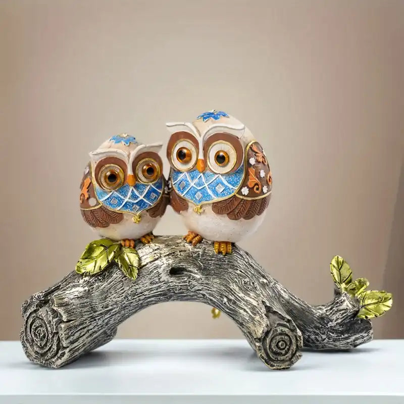 Decorative figurine of two owls on a branch with a beige background