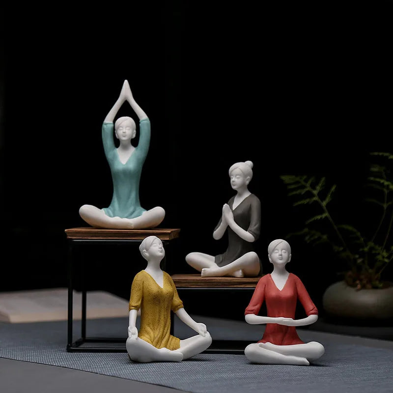 Four yoga-themed figurines in different colors on a dark background