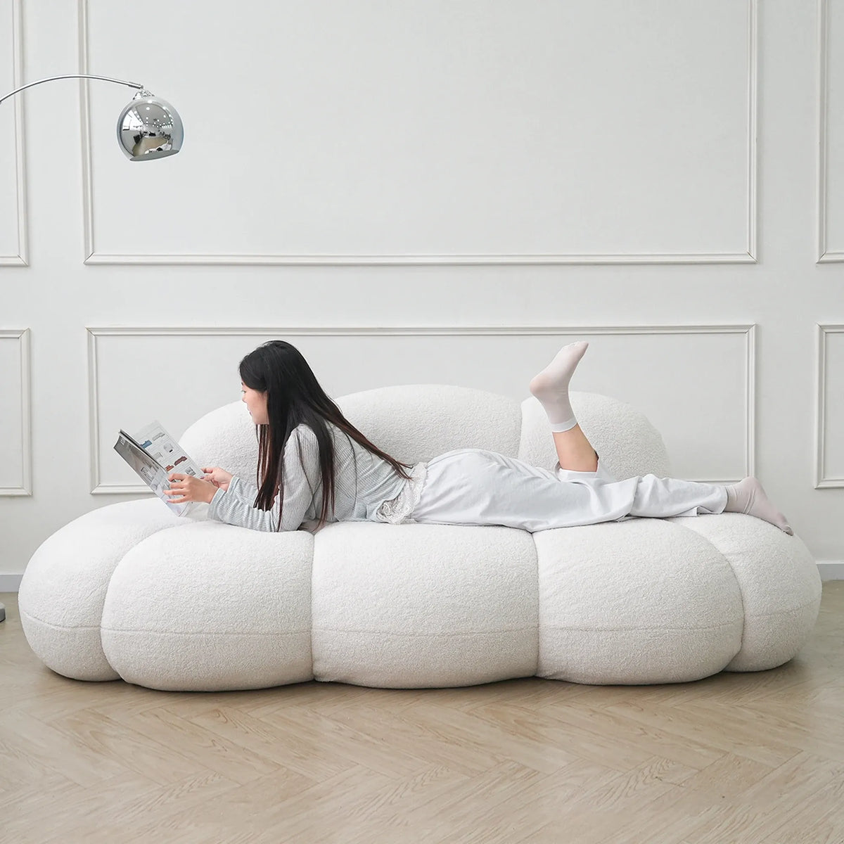 Person lying on a modern white bean bag chair in a minimalistic room.