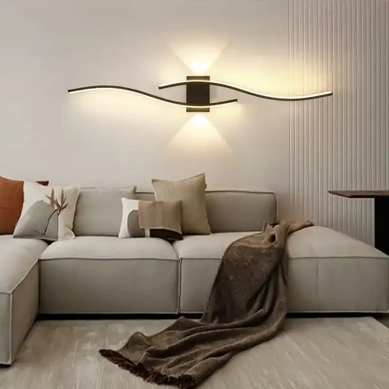 Modern living room with a beige sectional sofa, decorative pillows, and a wall-mounted light fixture.