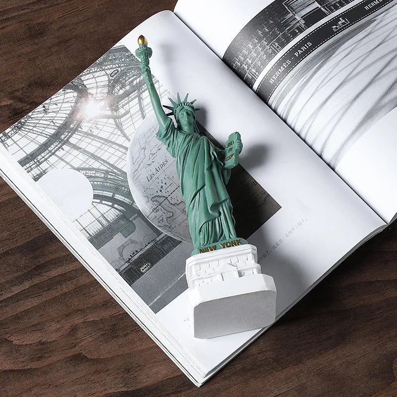 Statue of Liberty model on an open book with architectural illustrations