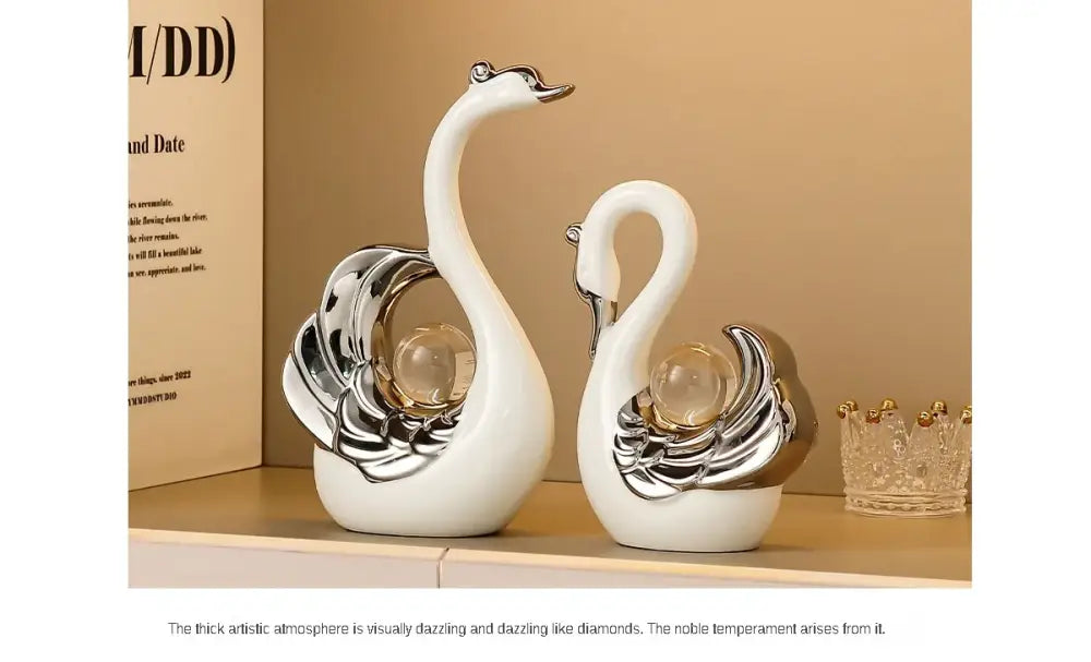 Two decorative swan figurines with silver and glass accents on a beige shelf.