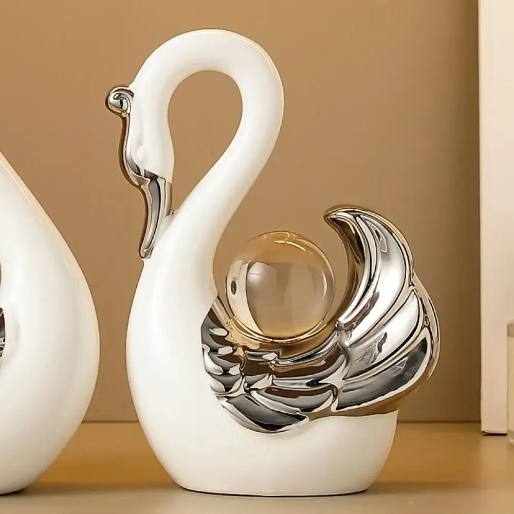 decorative swan figurines with silver and glass accents on a beige shelf.
