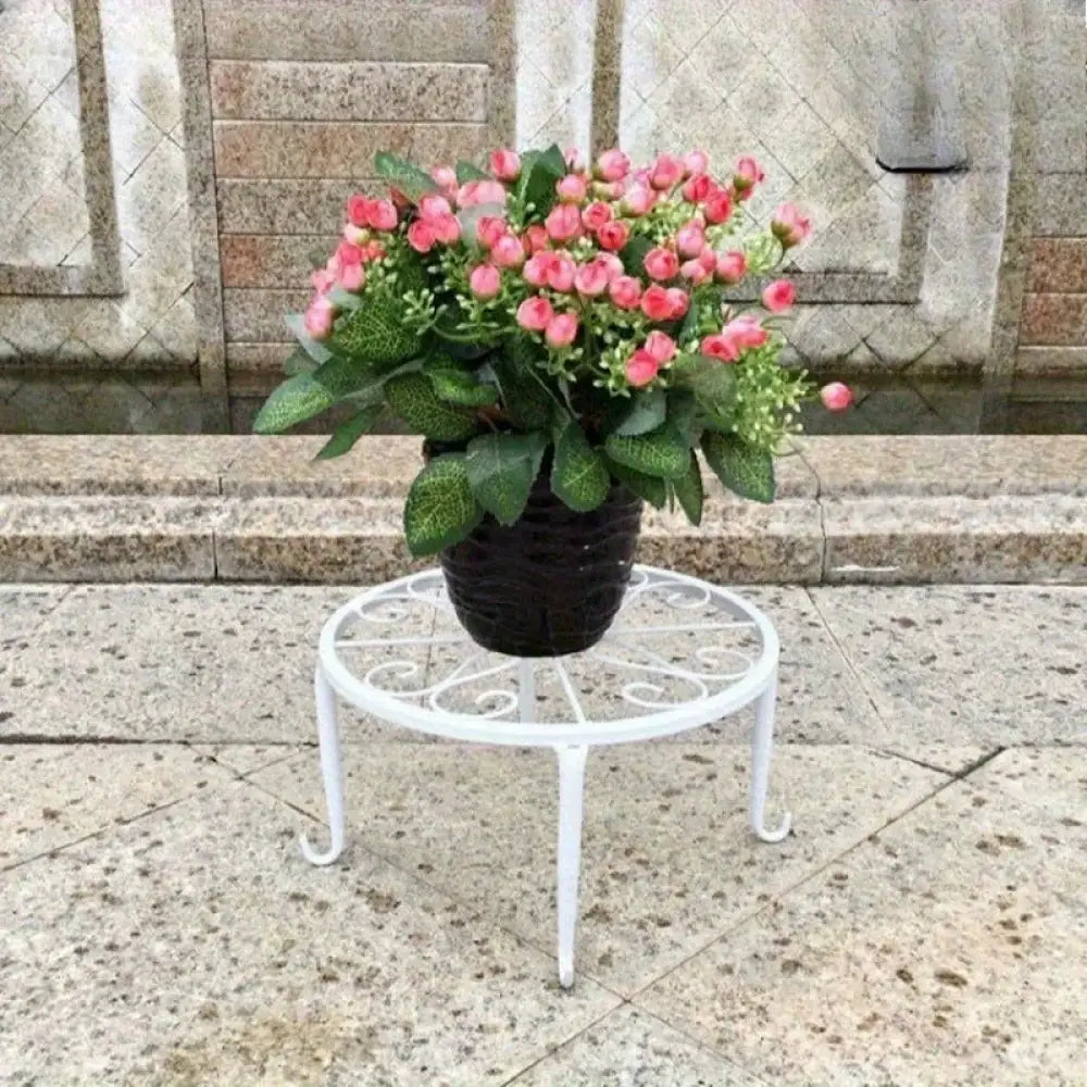 Potted plant with pink flowers on a decorative metal stand in front of stone steps.