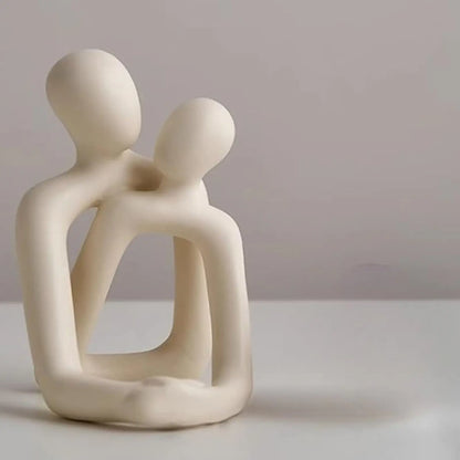Abstract sculpture of two figures embracing on a plain background