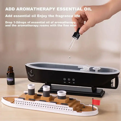 Aromatherapy diffuser with a hand adding essential oil and a bottle of essential oil on a wooden surface.
