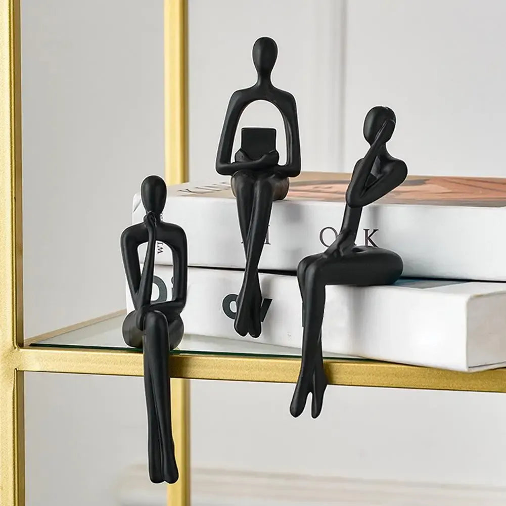 Black abstract figurines on a shelf with books