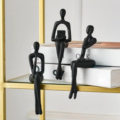 Black abstract figurines on a shelf with books