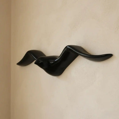 Black bird-shaped wall sculpture on a beige wall