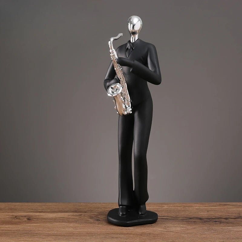 Black figurine of a person playing a saxophone on a wooden surface with a gray background