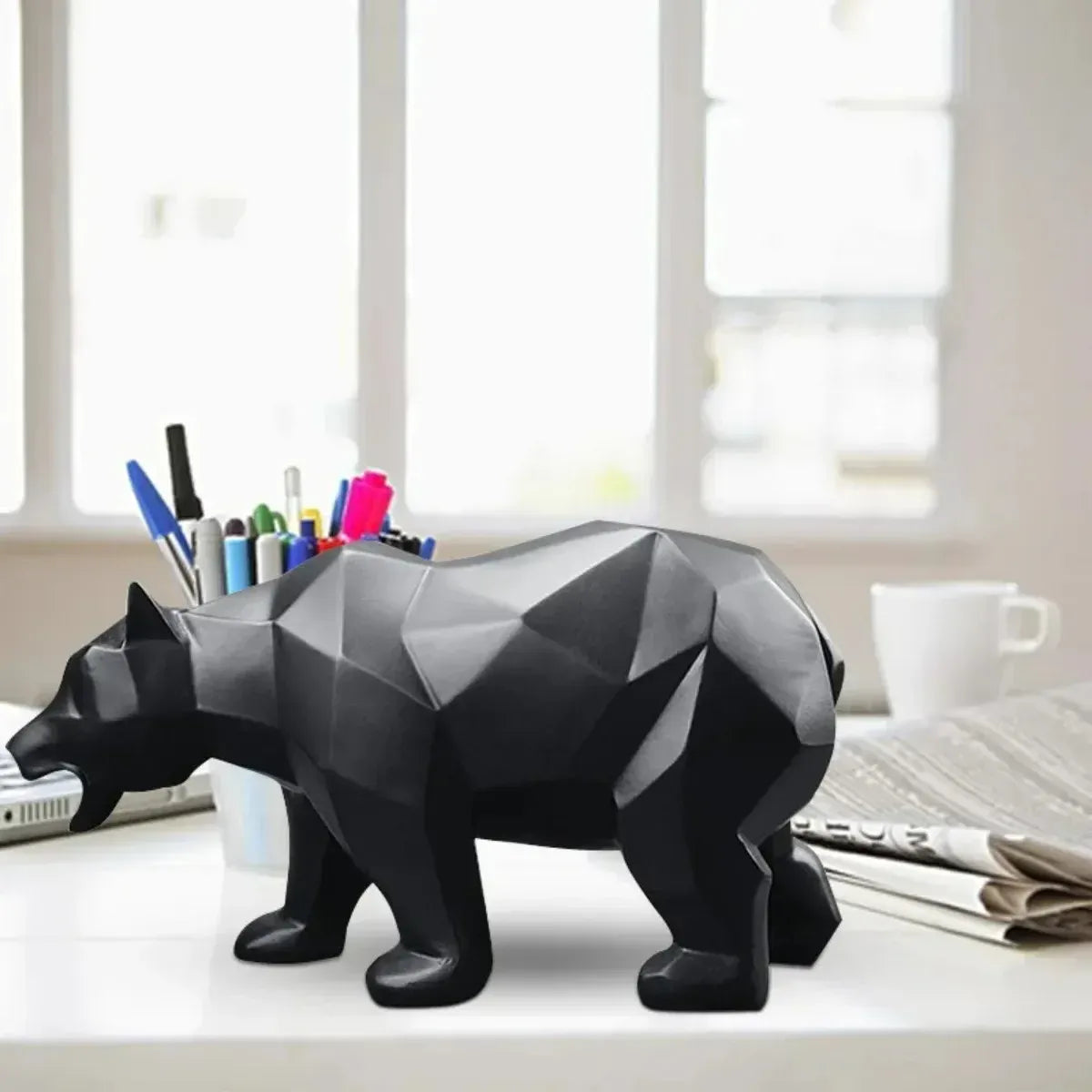 Black geometric bear on a desk with office supplies.