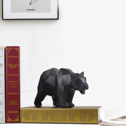 Black geometric bear figurine on a stack of books with a beige wall background