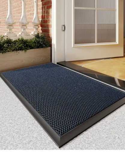 Blue doormat with textured pattern on a gray concrete floor outside a building entrance.