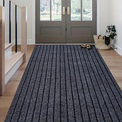 Blue striped rug in front of a gray door with shoes and a bag on it.