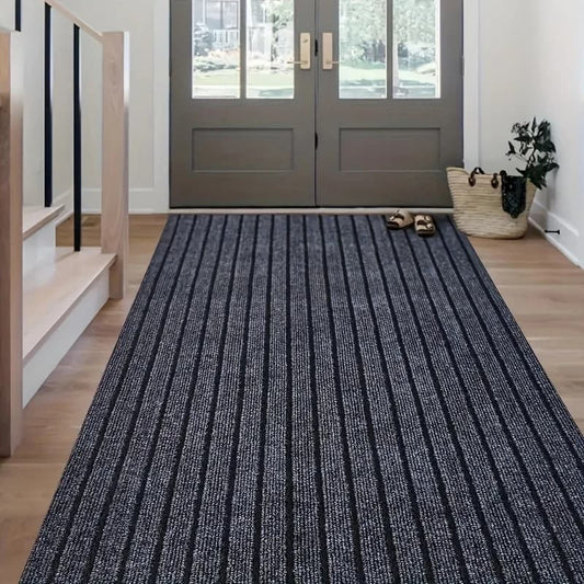 Blue striped rug in front of a gray door with shoes and a bag on it.