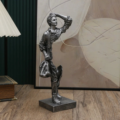 Bronze statue of a person on a wooden floor with a decorative wall in the background
