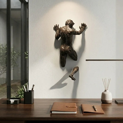 Bronze wall sculpture of a leaping figure on a modern interior wall.