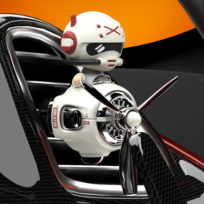 A car air freshener shaped like a robot with a propeller on a car vent.