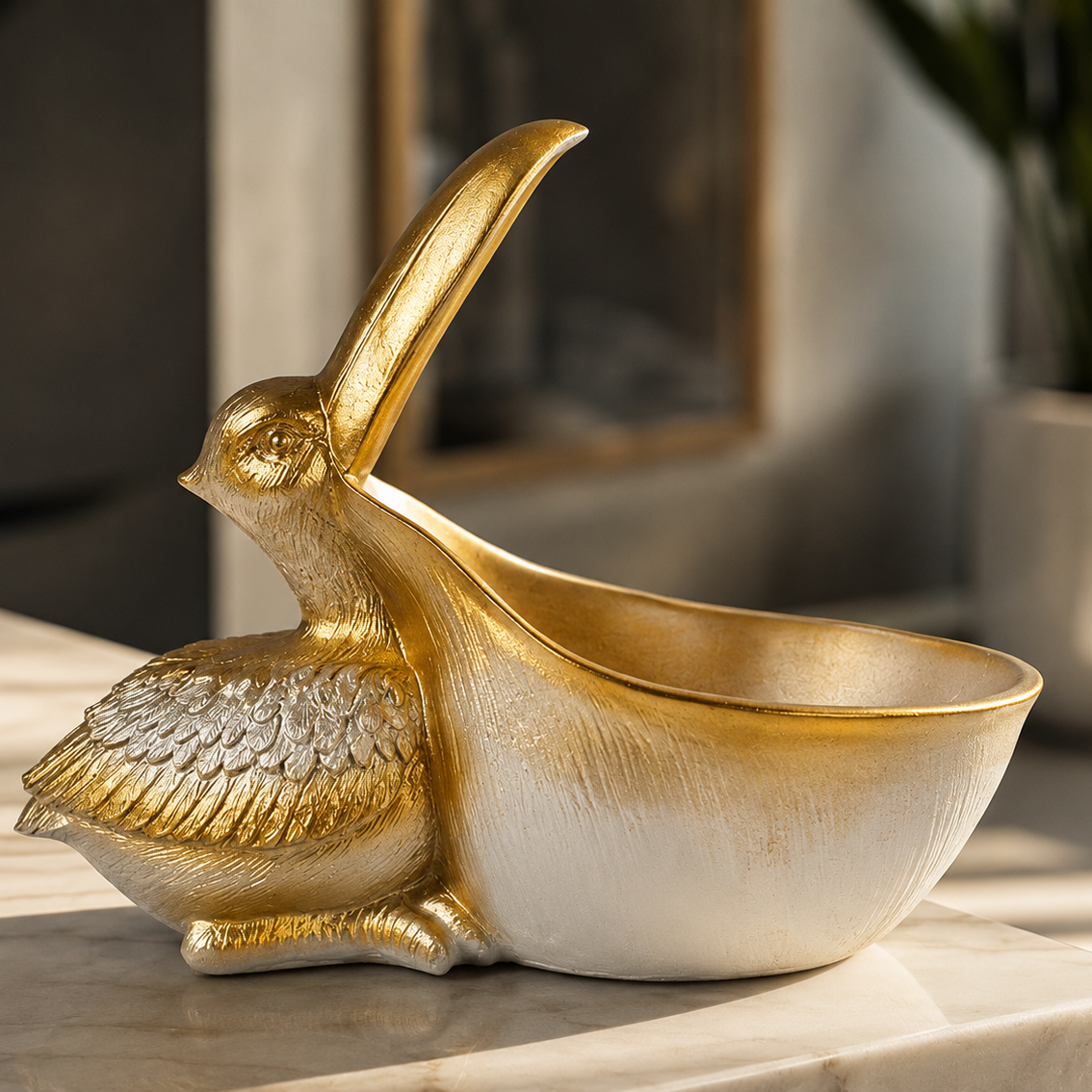 A decorative gold and white ceramic rabbit-shaped bowl with a long upright beak, displayed on a light marble surface in a softly blurred indoor setting.