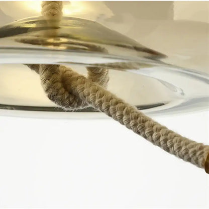 Close-up of a ceiling light fixture with a rope-like pull cord on a white background