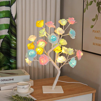 Colorful LED tree lamp on a wooden table with books and a cup in the background.