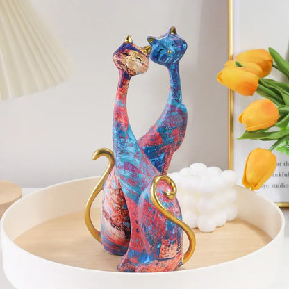 Colorful ceramic cat figurines on a decorative tray with flowers in the background