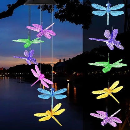 Colorful dragonfly-shaped LED lights hang against a night sky with a body of water in the background.