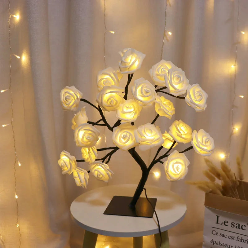 Decorative LED lamp shaped like a tree with white rose flowers on a small round table.