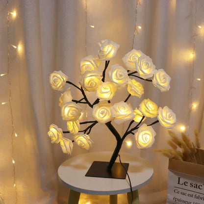 Decorative LED lamp shaped like a tree with white rose flowers on a small round table.