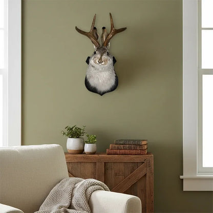 Decorative animal head with antlers mounted on a wall in a room with a sofa and wooden side table.