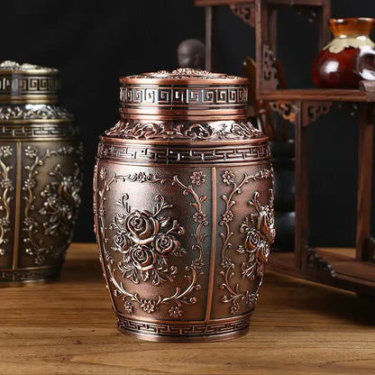 Decorative bronze urn with intricate designs on a wooden surface.