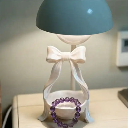 Decorative lamp with a bow and a purple bracelet on a table.