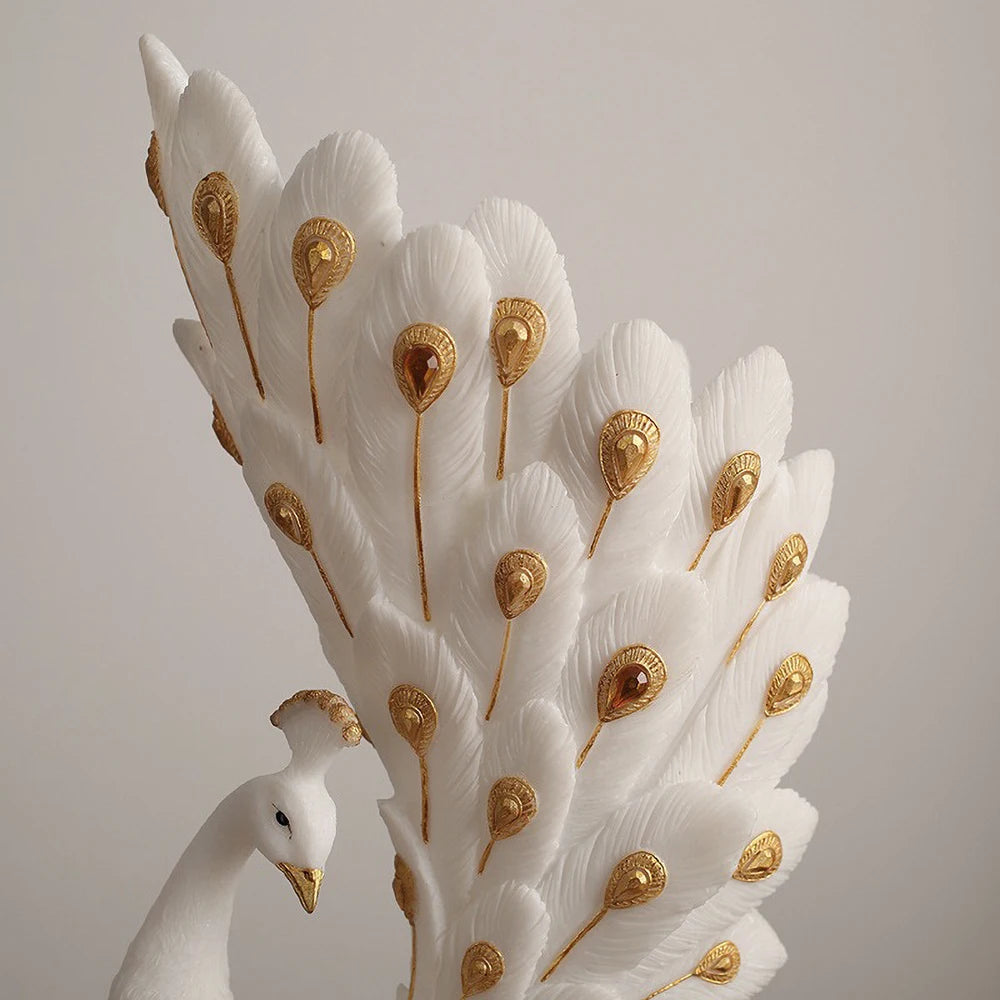 Decorative peacock feather sculpture with gold accents on a plain background