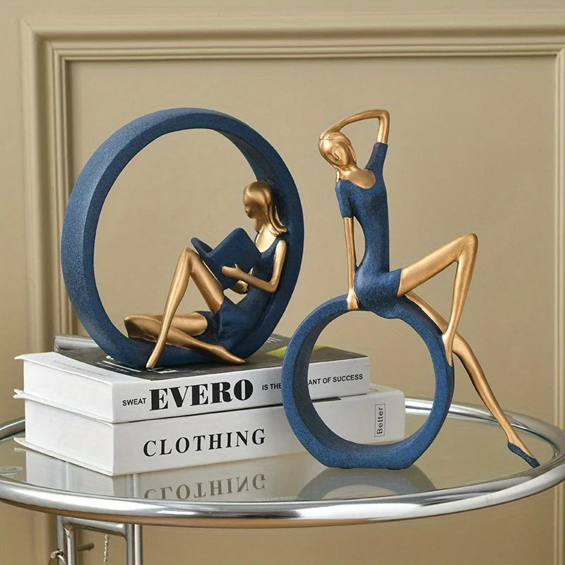 Decorative sculpture of two people on a circular platform with books underneath, set against a beige wall.