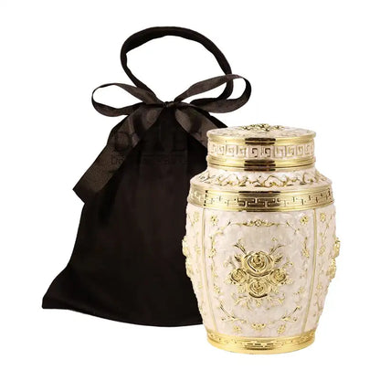 Decorative urn with gold accents and a black satin bag on a white background