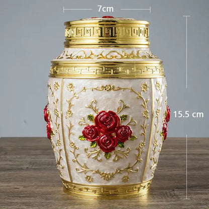 Decorative urn with gold accents and red roses on a wooden surface