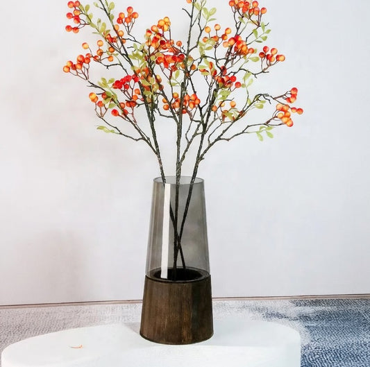 Decorative vase with branches and berries on a white surface