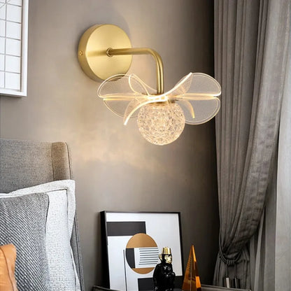 Decorative wall lamp with gold finish and glass shade in a room setting.