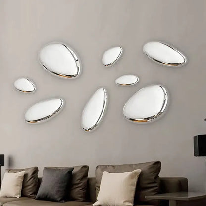 Decorative wall mirrors shaped like pebbles on a neutral wall above a sofa.