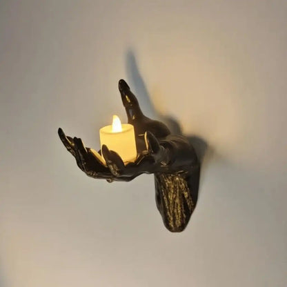 Decorative wall sconce shaped like a hand holding a candle on a plain background