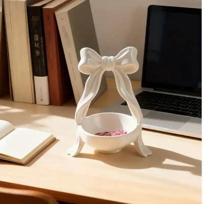 Decorative white hourglass-shaped object on a desk with books and a laptop in the background
