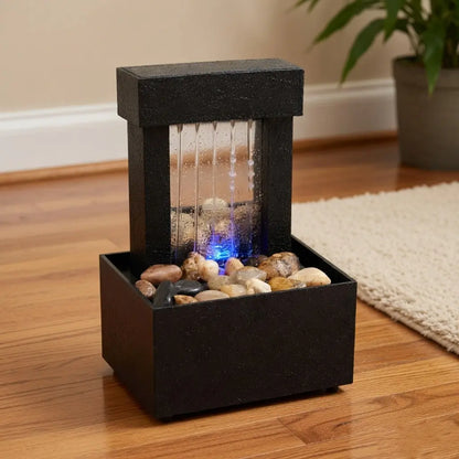Tabletop water fountain with rocks and LED light on a wooden floor.