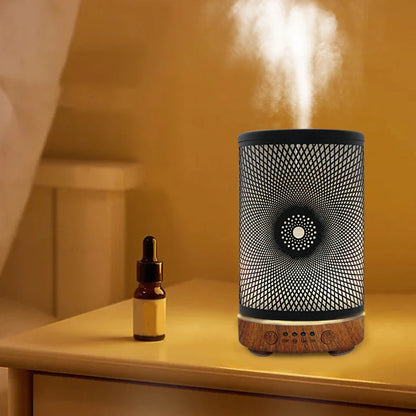 Diffuser emitting steam on a wooden surface with an essential oil bottle next to it.