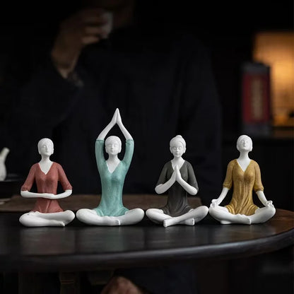 Four figurines in various yoga poses on a dark surface with a blurred background
