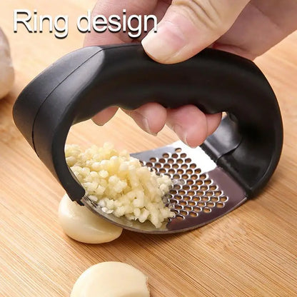 Garlic press with garlic being crushed on a wooden surface
