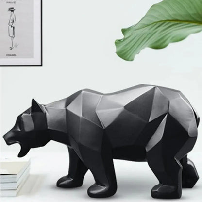 Geometric black and gray bear statue on a white surface with a plant leaf in the corner.