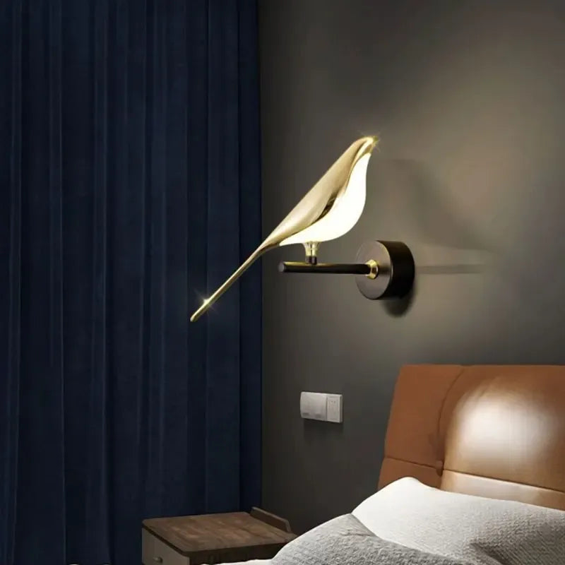 Gold bird-shaped wall lamp on a dark wall next to a bed