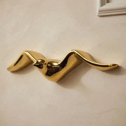 Gold Bird-shaped wall hook on a beige wall